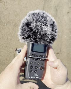 Andrey's hands fitting a fur windscreen on the Zoom H5 recorder before a take